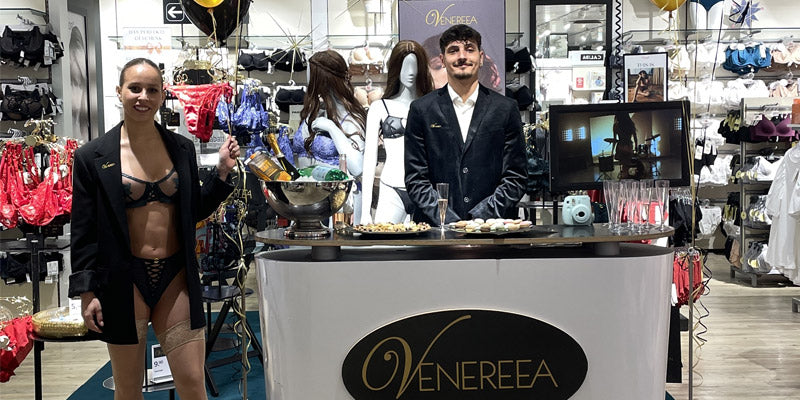 Verkaufsfläche Lingerie, Eine Dame in Unterwäsche mit Blazer und ein Herr im Anzug stehen ebenfalls auf der Verkaufsfläche. Zu sehen ist auch ein kleiner Apéro